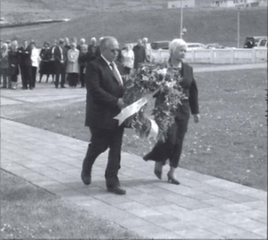 Hjónin ágúst og Ása leggja krans við minnisvarðann á kirkjulóðinni.png
